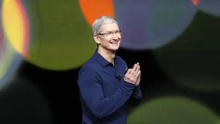 Man in blue shirt smiling on stage, colorful background, Kraftshala.