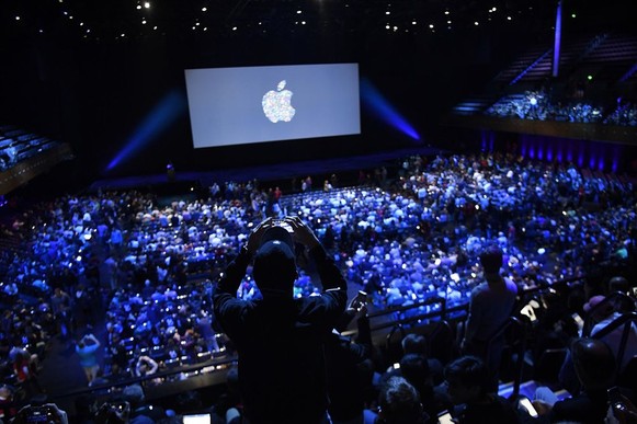 Apple event with audience in a large, dimly lit auditorium.