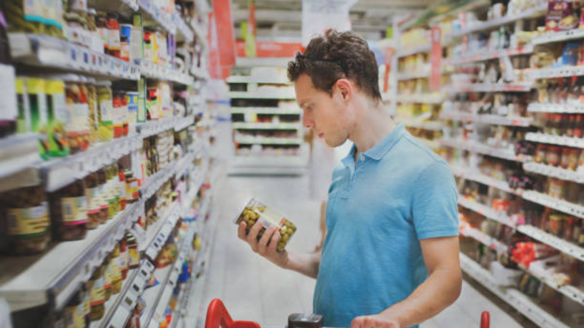 Shopper examines product in grocery aisle, Kraftshala branding.