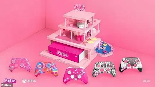 Barbie Xbox controllers and pink dollhouse set against a pink backdrop.